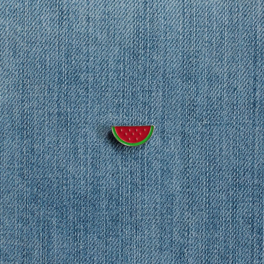 Watermelon enamel pin on blue denim fabric, cute fruit accessory