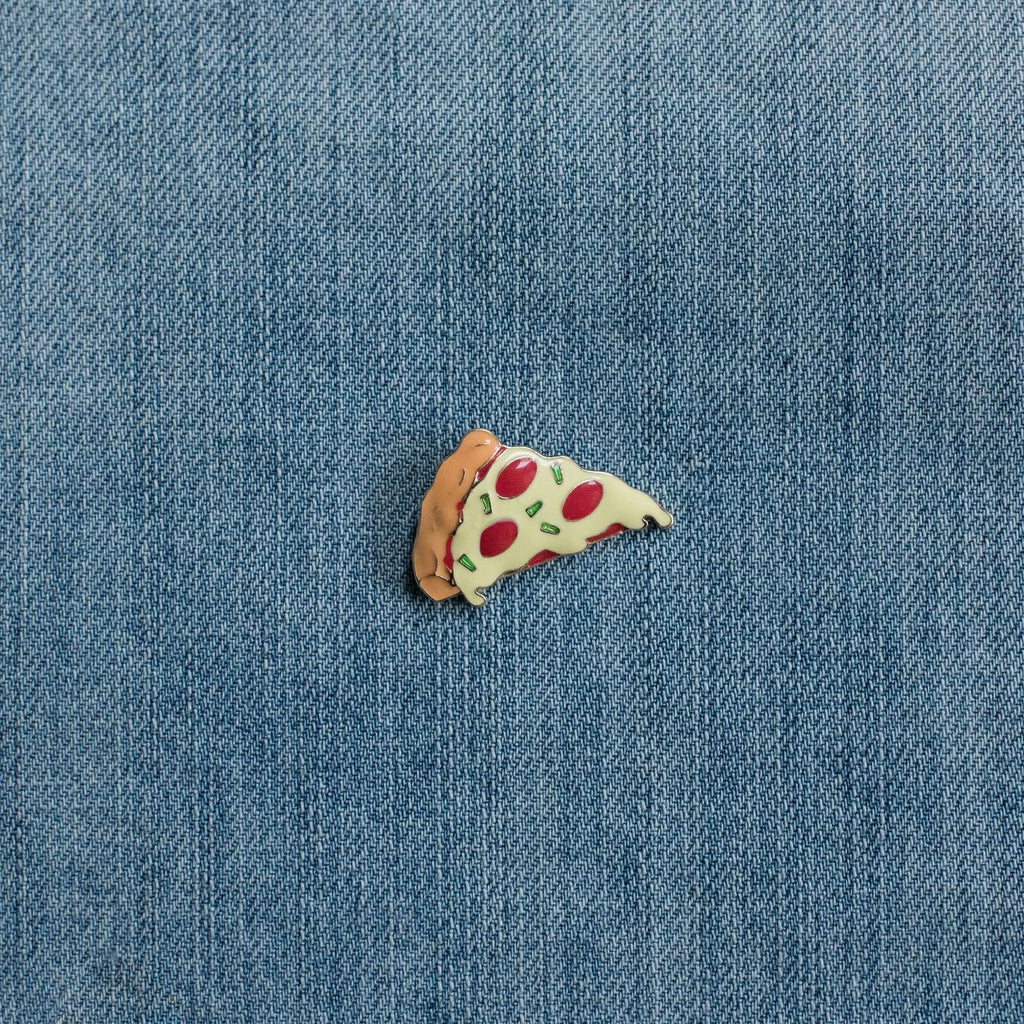 Pizza slice enamel pin on blue denim fabric background