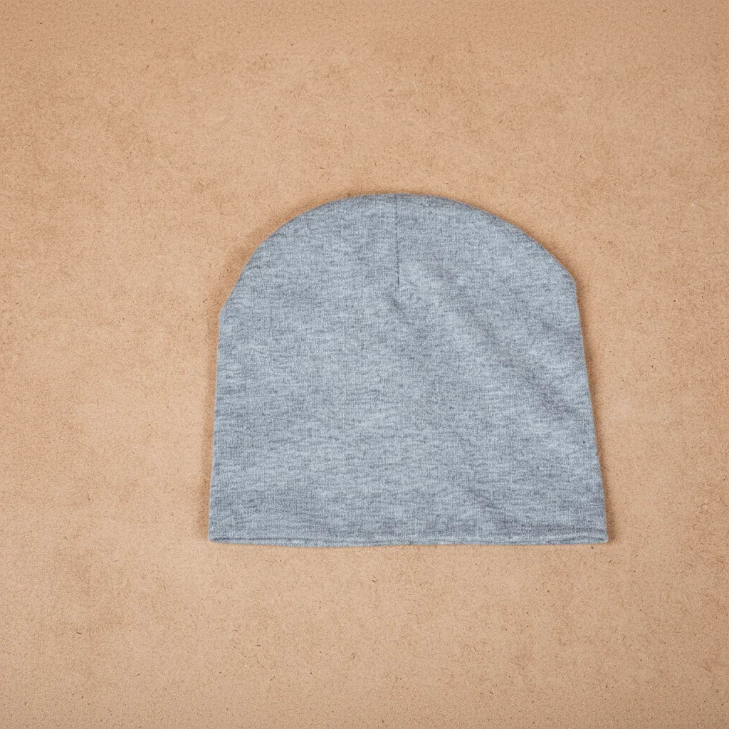 Gray cotton beanie hat flat lay on tan textured background