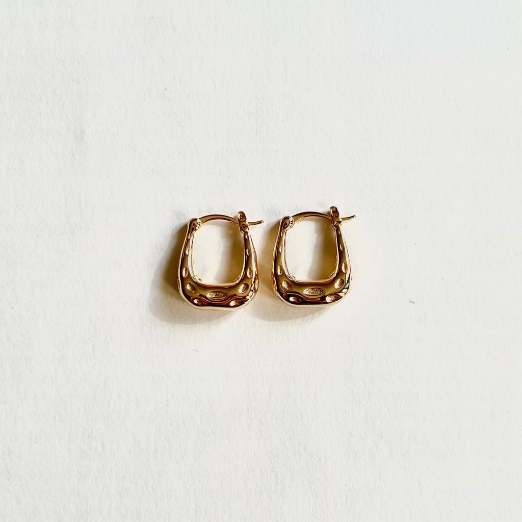 Gold textured hoop earrings on white background, modern jewelry accessory