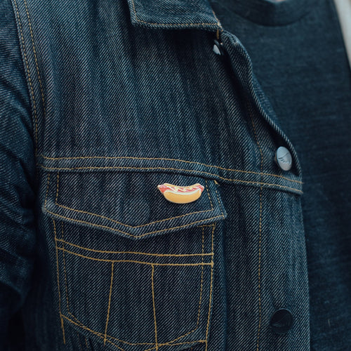Hot dog enamel pin on denim jacket pocket