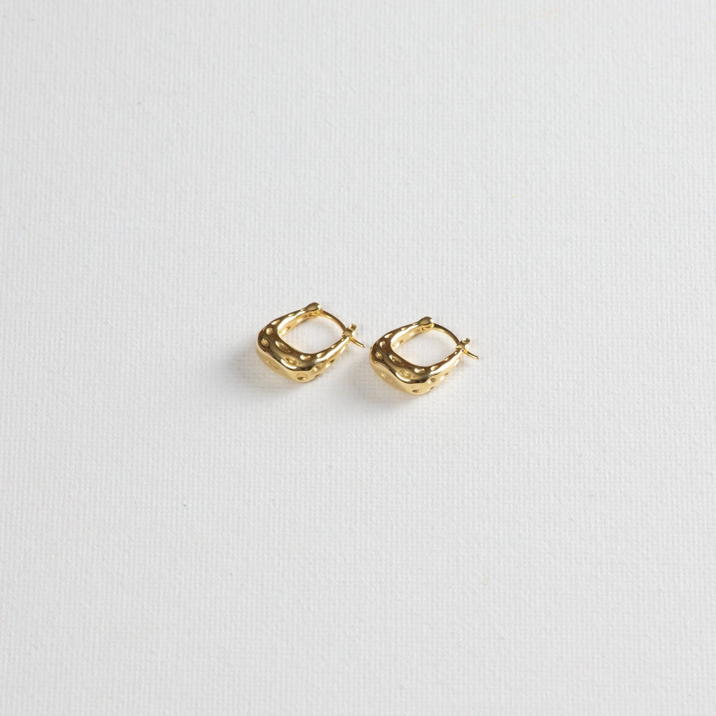 Gold textured hoop earrings on white background