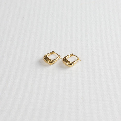 Gold textured hoop earrings on white background
