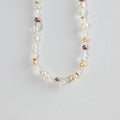Multi-colored freshwater pearl and gold bead necklace on white background
