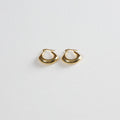 Gold chunky hoop earrings with smooth finish on white textured background