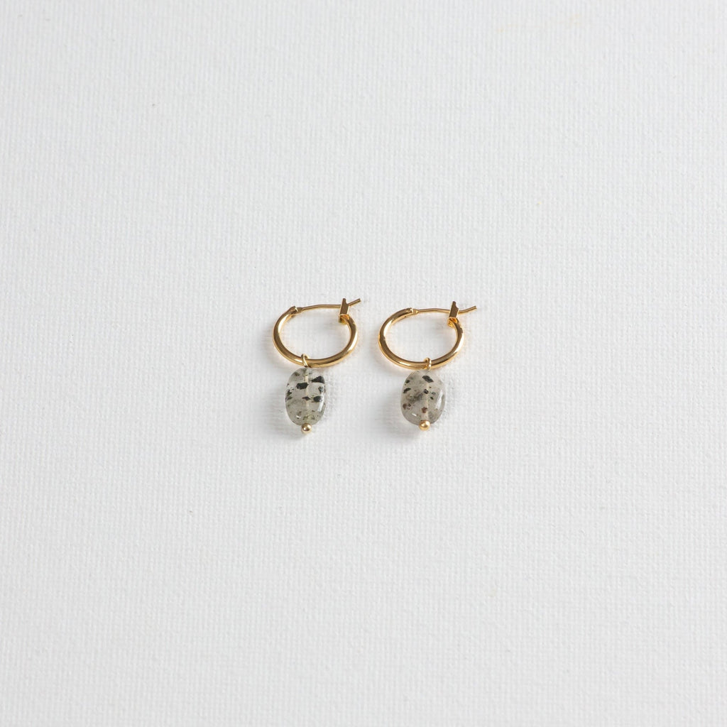 Gold hoop earrings with oval dalmatian jasper stone charms on white background