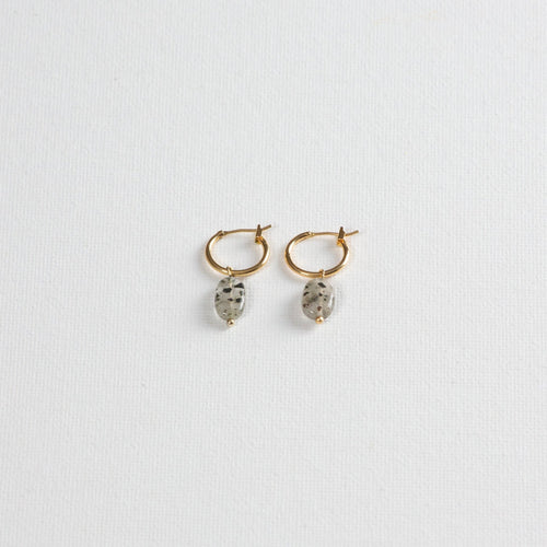 Gold hoop earrings with oval dalmatian jasper stone charms on white background
